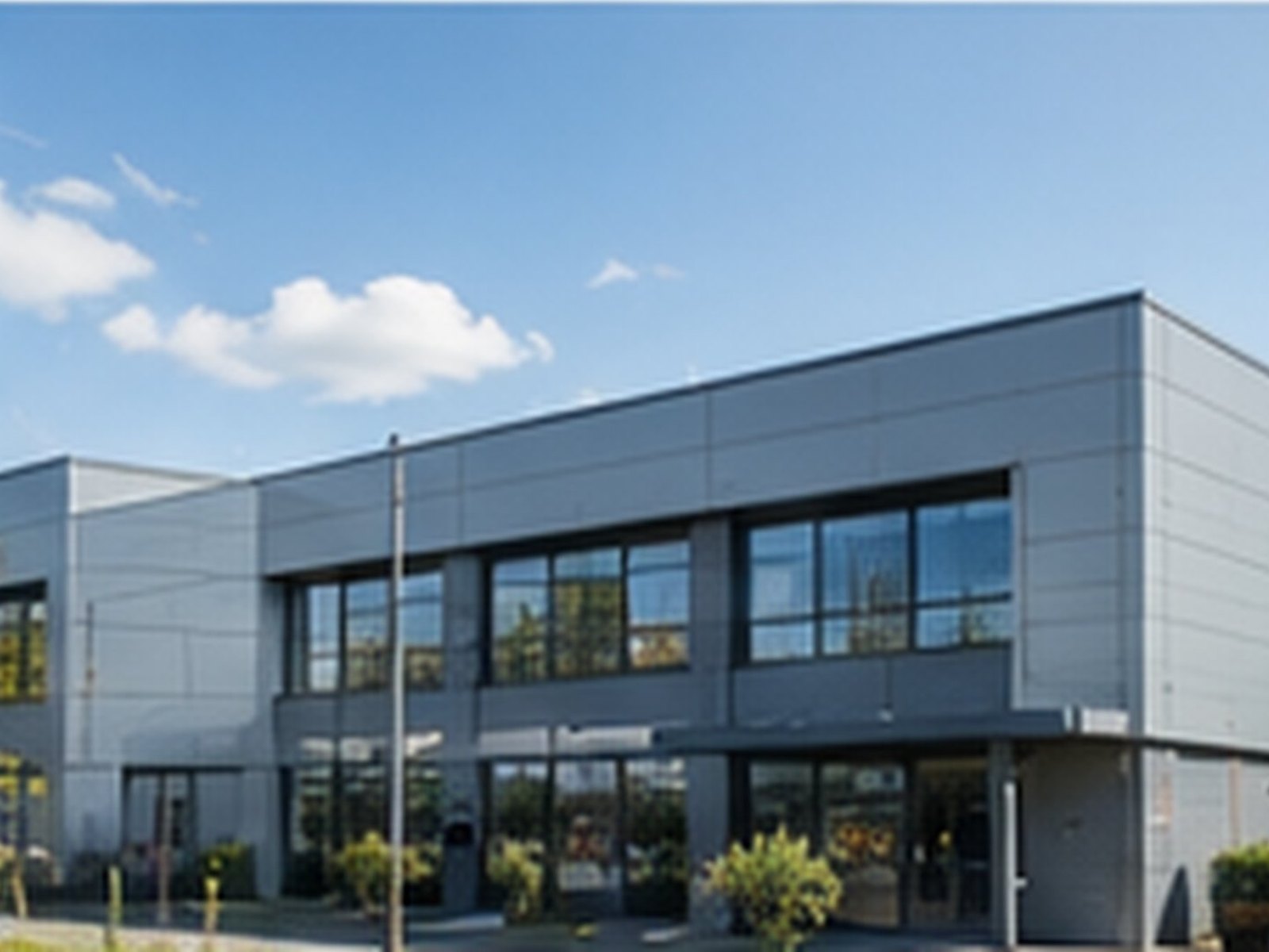 A modern two-storey commercial building on a landscaped business park